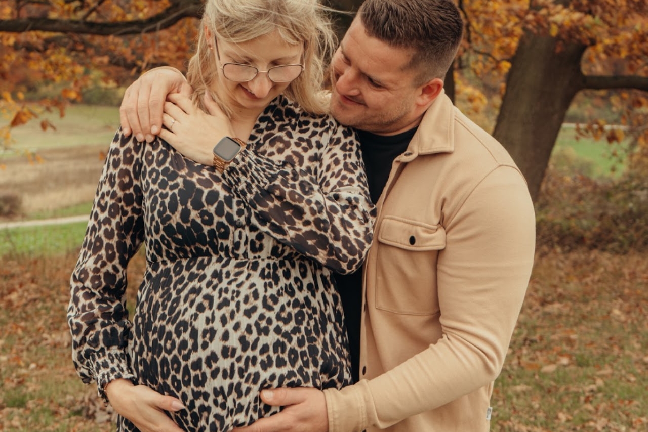 Schwangere hält liebevoll ihren Babybauch im Freien