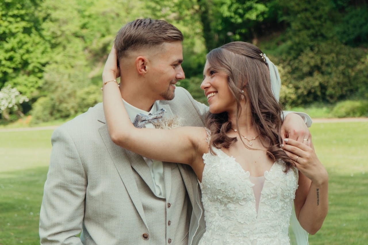 Brautpaar hält Hände vor der Kirche im Sonnenlicht