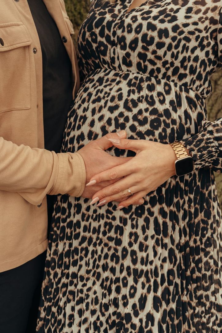 Nahaufnahme: Werdender Vater hält zärtlich die Hand seiner schwangeren Partnerin am Babybauch