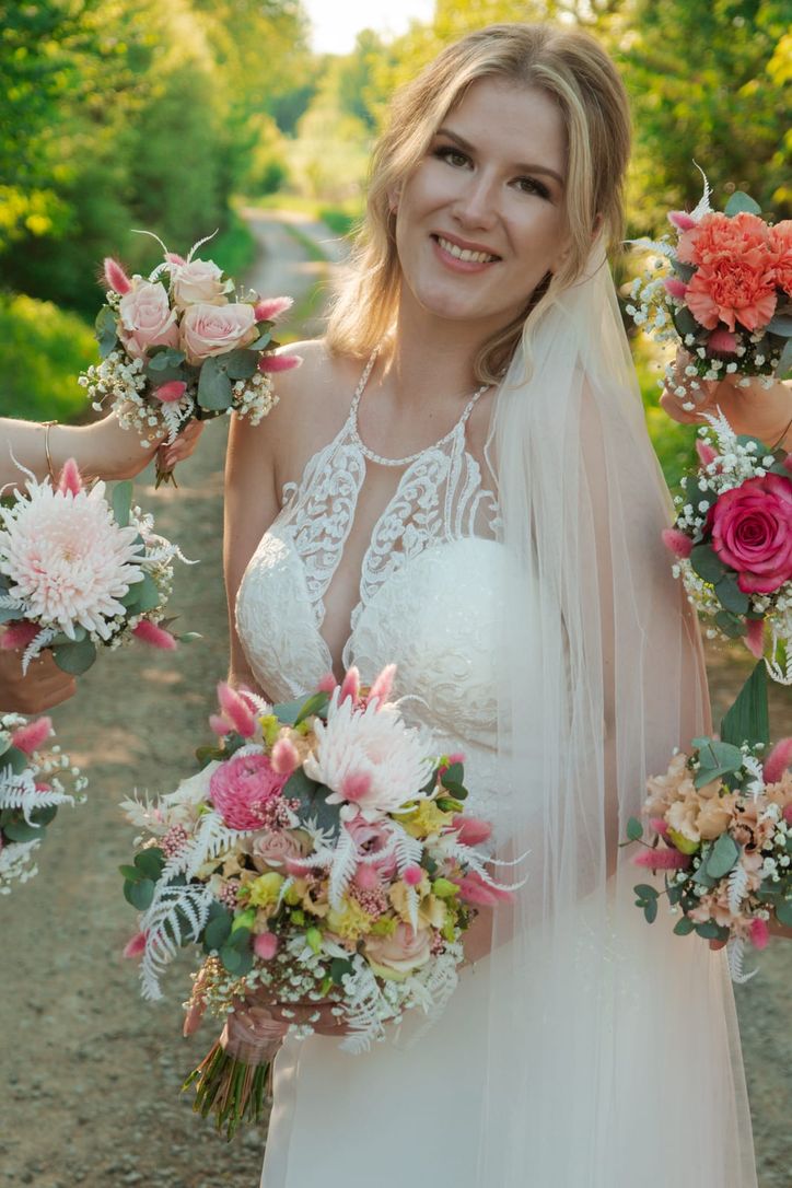 Porträt der lächelnden Braut mit Blumenkranz im Haar auf einem Feldweg