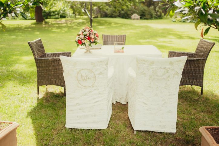 Festlich gedeckter Sitzplatz des Brautpaares mit Spitzen-Stuhlhussen im Garten
