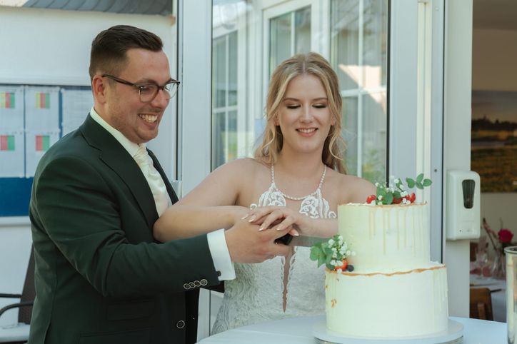 Brautpaar schneidet gemeinsam die Hochzeitstorte an