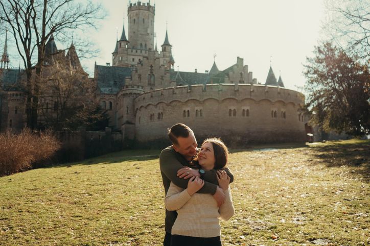 Paar umarmt sich lächelnd vor Schloss Marienburg