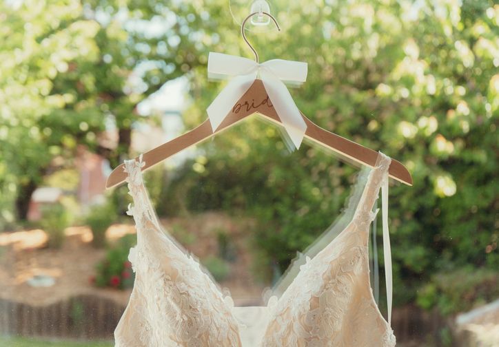 Brautkleid hängt mit Schleife am Fenster im Gegenlicht